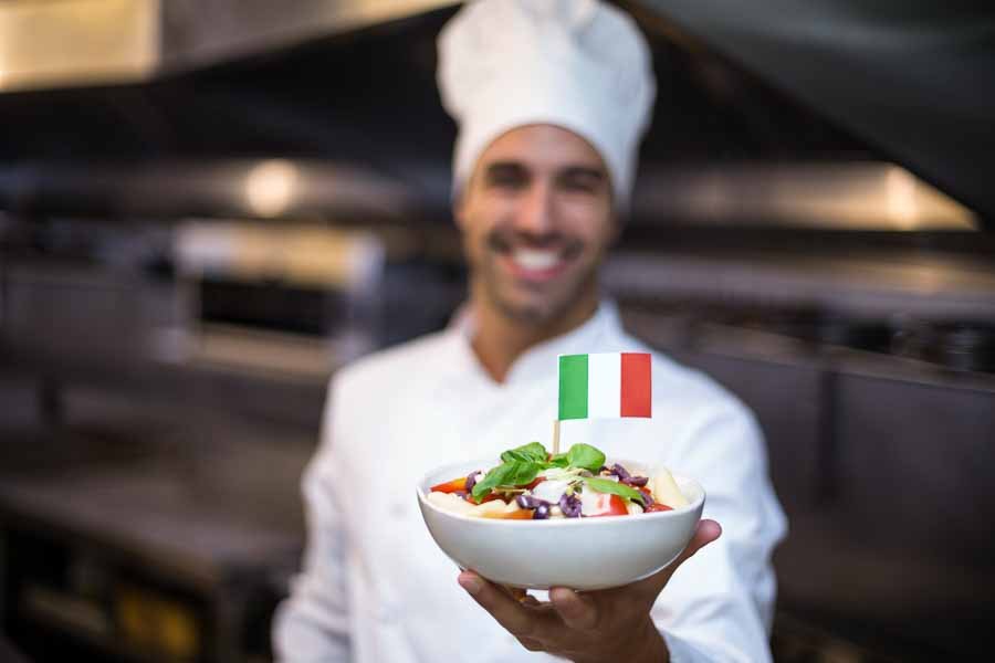 Handsome,Chef,Presenting,Meal,With,Italian,Flag,In,A,Commercial
